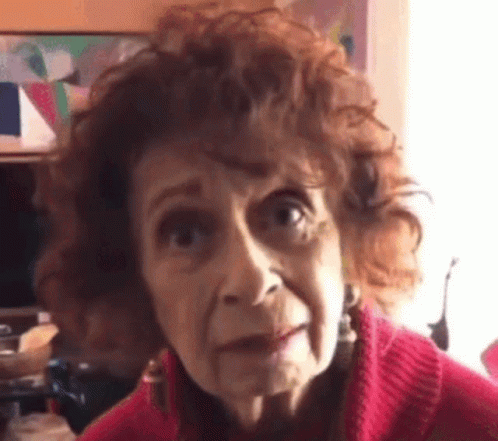 Curly Haired Elderly Woman In Red Sweater Making Funny Face GIF