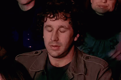 Curly Haired Man in Crowd Hand on Chin Eyes Closed
