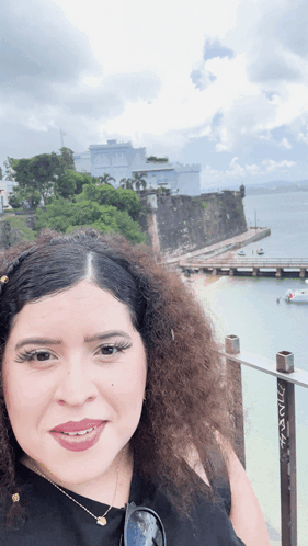 Curly Haired Woman by Water and Building