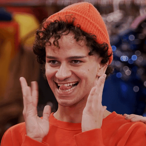 Curly Haired Young Man In Orange Hat And Sweater GIF
