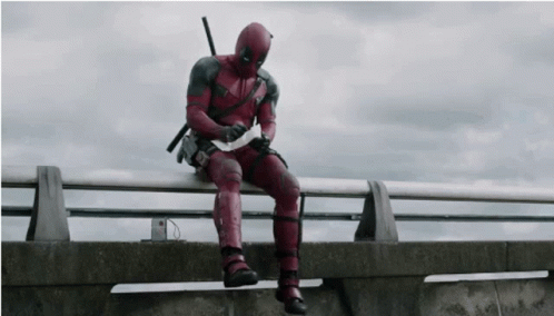 Deadpool Man Sitting on Railing Holding Paper