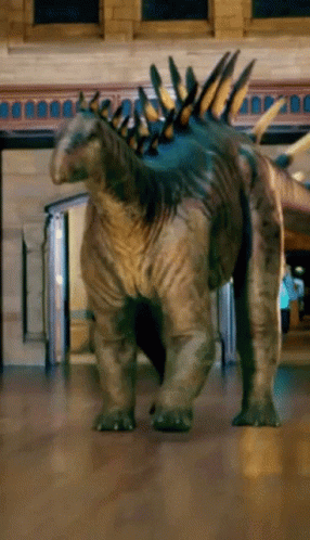 Dinosaur On Wooden Floor Near Brick Building GIF