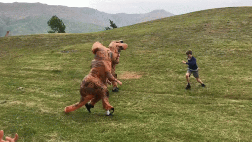 Dinosaur Suit Chasing Kid On The Hill GIF