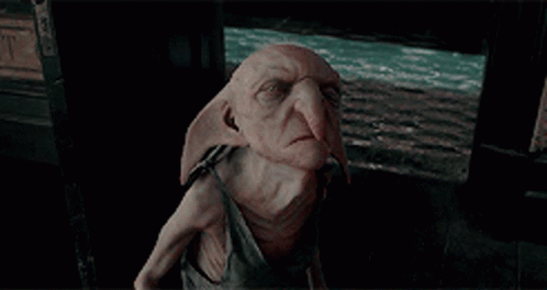 Dobby From Harry Potter Sitting In Dark Room GIF