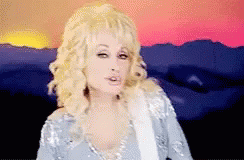 Dolly Parton Standing in Front of Sunset Holding Guitar