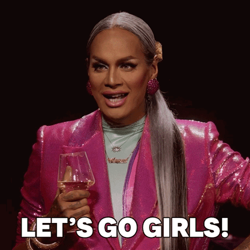Drag Queen in Pink Jacket Holding Wine Saying Let's Go Girls