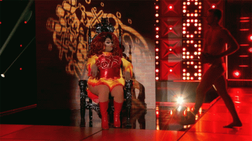Drag Queen Sitting on Throne With Man Behind