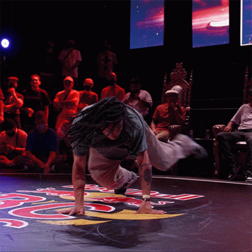 Dreadlocked Man Handstanding on Floor with Letter R
