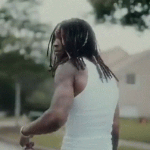 Dreadlocked Man in White Tank Top by Building