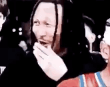 Dreadlocked Man Laughing Covering Mouth in Crowd