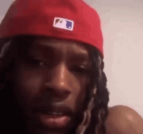 Dreadlocked Man With Red Hat Looking at Camera