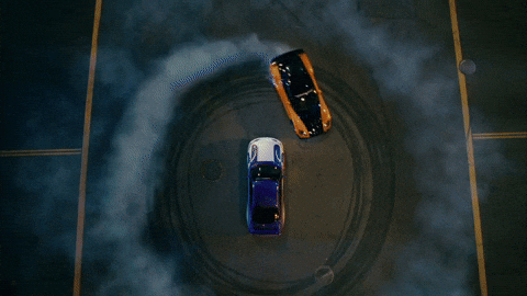 Drift Cars Creating Donuts Around A Car GIF