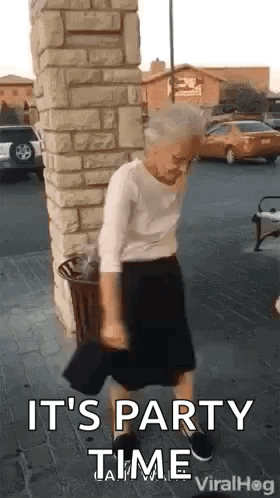 Elderly Woman Dancing by Brick Building