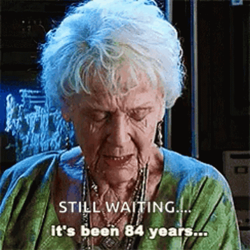 Elderly Woman Gray Hair Green Shirt Says Still Waiting It's Been 84 Years