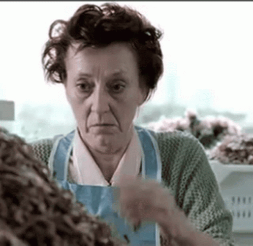 Elderly Woman In Blue Apron Standing At Counter GIF