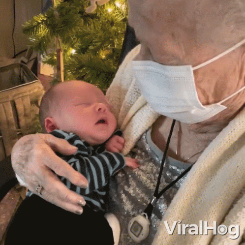 Elderly Woman in Face Mask Holding Baby