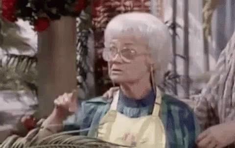 Elderly Woman in Glasses and Apron Sitting