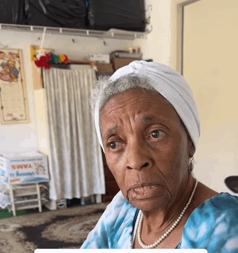 Elderly Woman in White Turban and Pearls Saying Yams