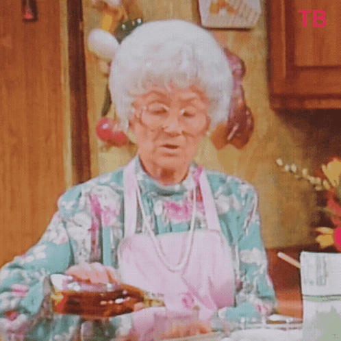 Elderly Woman Pouring Syrup Into Glass While Wearing Apron