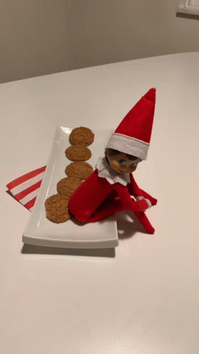 Elf On The Shelf Sits On Plate With Cookies GIF