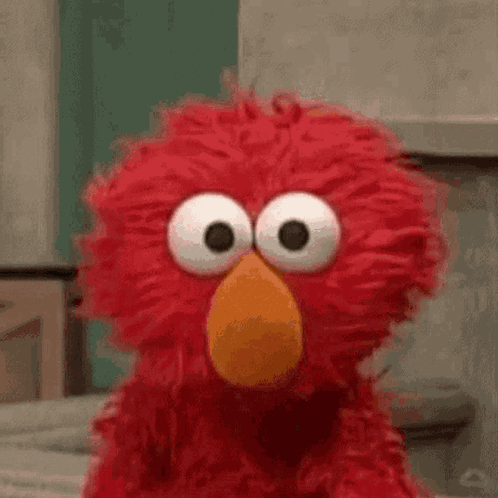 Elmo From Sesame Street Is Making A Funny Face With His Big Eyes . GIF