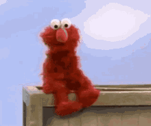 Elmo From Sesame Street Is Sitting On A Balcony Looking Out The Window . GIF