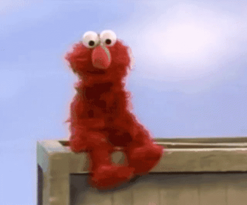 Elmo From Sesame Street Is Sitting On A Wooden Box GIF