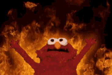 Elmo From Sesame Street Is Standing In Front Of A Fire GIF