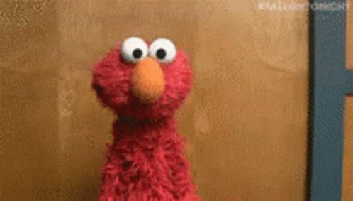 Elmo From Sesame Street Is Standing In Front Of A Wall . GIF