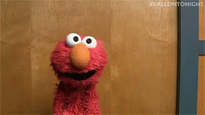 Elmo From Sesame Street Is Standing In Front Of A Wooden Door And Looking At The Camera . GIF