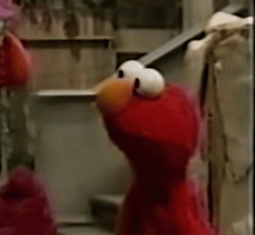 Elmo From Sesame Street Is Standing On A Set Of Stairs And Looking At The Camera . GIF
