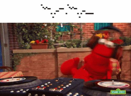 Elmo From Sesame Street Sits At A Table With A Remote Control GIF
