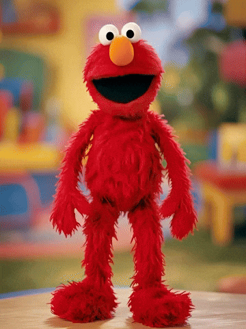 Elmo From Sesame Street Stands On A Wooden Table GIF