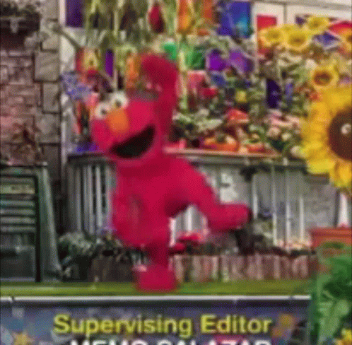 Elmo Is Dancing In Front Of A Sign That Says Supervising Editor GIF