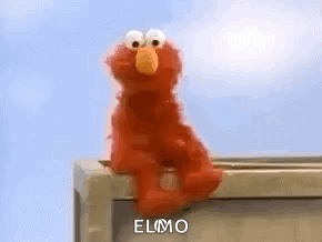 Elmo The Sesame Street Character Is Sitting On A Box On A Balcony . GIF