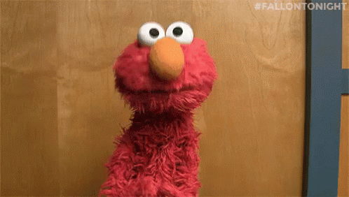Elmo The Sesame Street Character Is Standing In Front Of A Wooden Wall . GIF