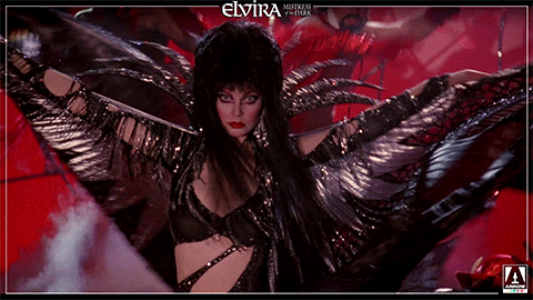 Elvira Spinning While Raising Her Outfit GIF