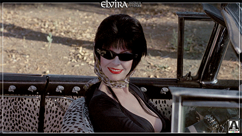 Elvira Waving Hello From Her Car GIF
