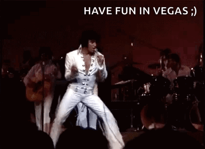 Elvis Presley Is Dancing On Stage In Front Of A Crowd While Playing A Guitar . GIF