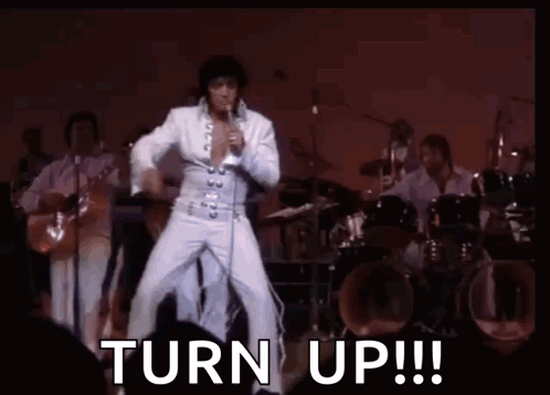 Elvis Presley Is Dancing On Stage While Singing Into A Microphone With The Words `` Turn Up ! '' GIF
