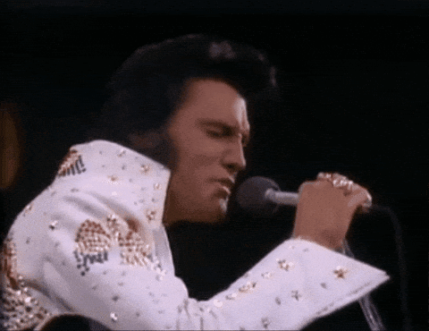 Elvis Presley Is Singing Into A Microphone While Wearing A White And Gold Suit . GIF