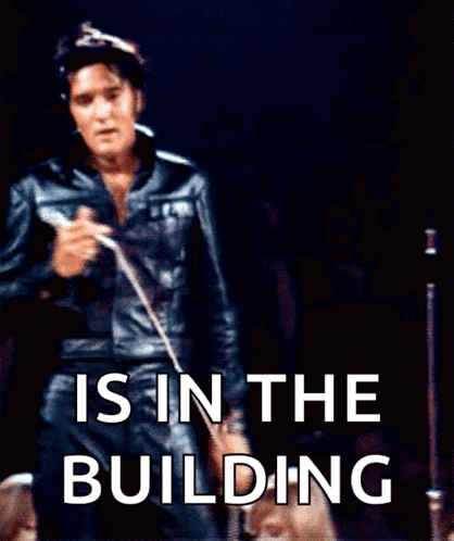 Elvis Presley Singing Into A Microphone With The Words " Is In The Building " Behind Him GIF