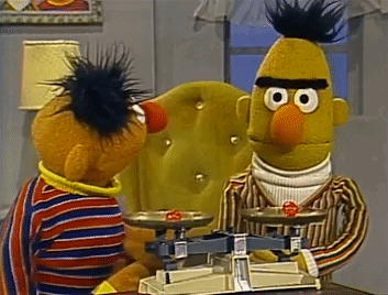 Ernie And Bert From Sesame Street Are Sitting At A Table With A Scale GIF