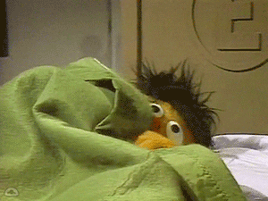 Ernie From Sesame Street Is Laying In Bed With A Green Blanket GIF