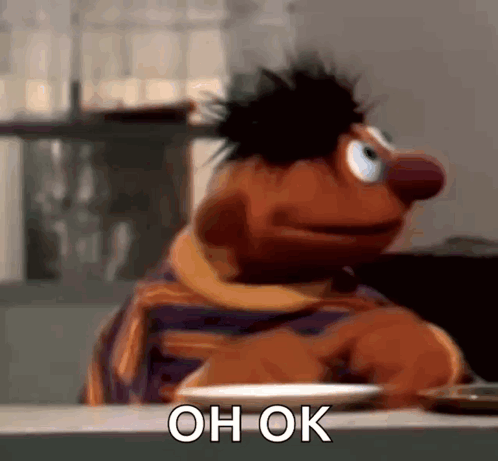 Ernie From Sesame Street Is Sitting At A Table With A Plate In Front Of Him And Says `` Oh Ok '' . GIF