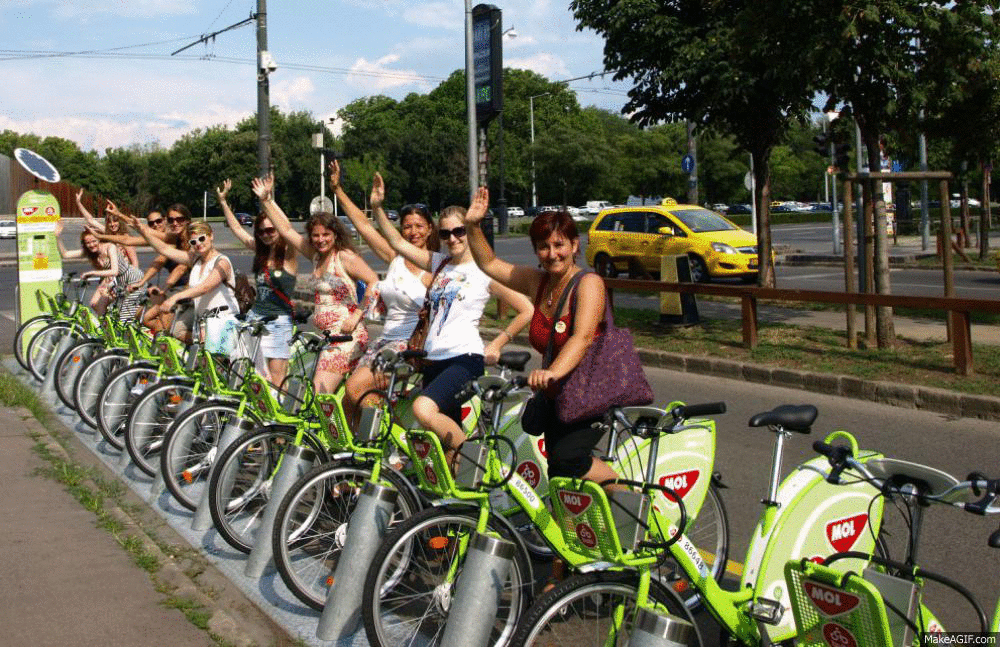 Female Bicycle Riders Synchronize Wave GIF