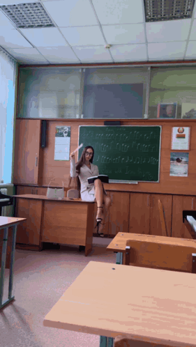 Female Teacher at Desk with Blackboard and Calendar