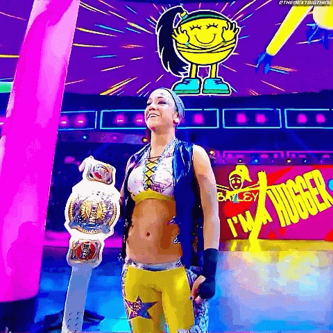 Female Wrestler Holding Championship Belt in Front of I'm a Hugger Sign