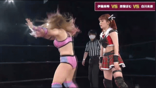 Female Wrestler Next to Wrestler in Red Pants With X on Pocket