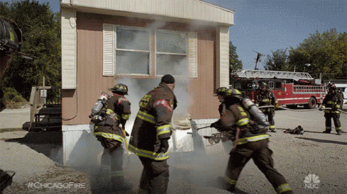 Firefighters In Front Of Mobile Home With Smoke GIF